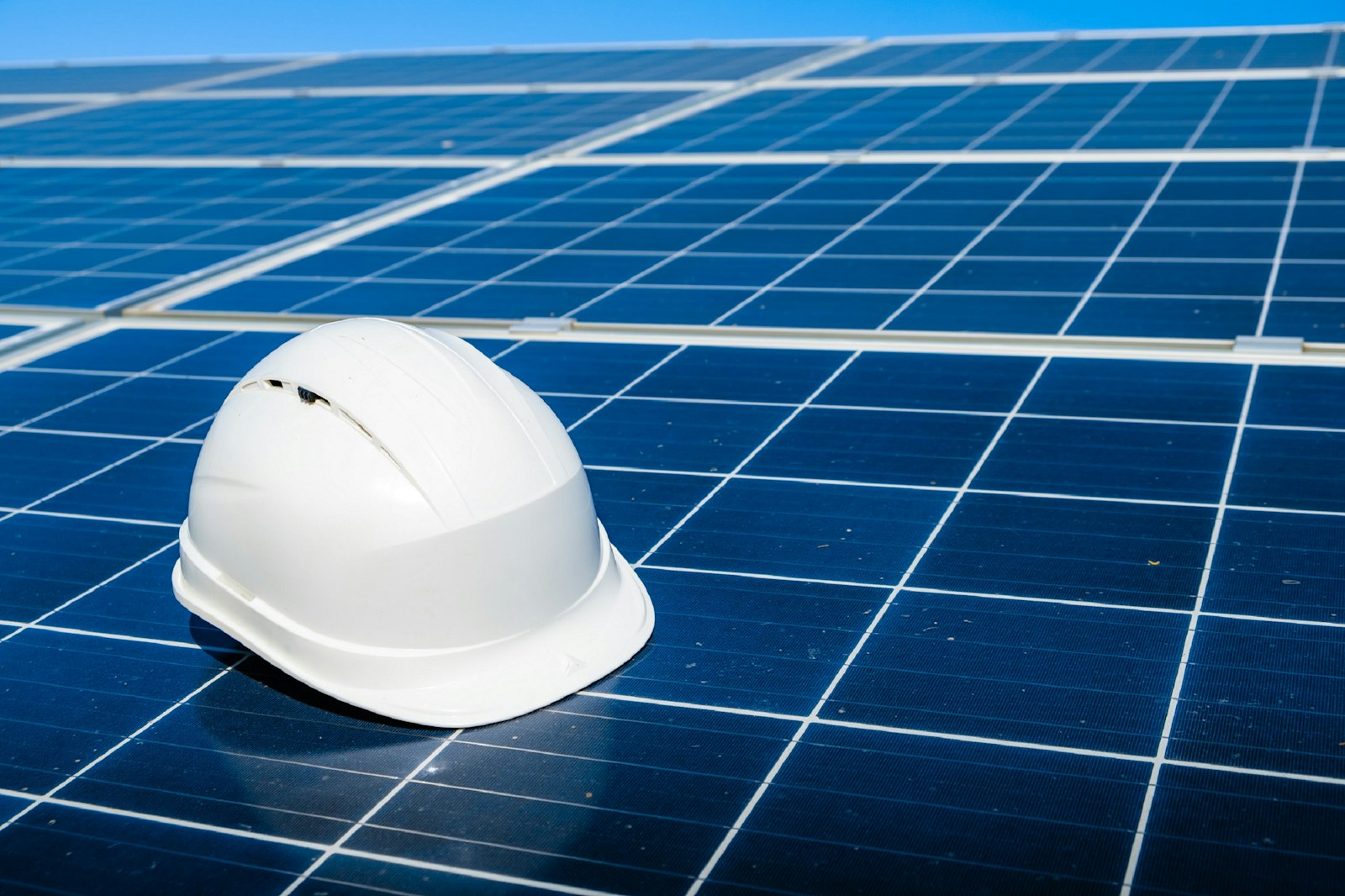 White hard hat resting on a row of solar modules